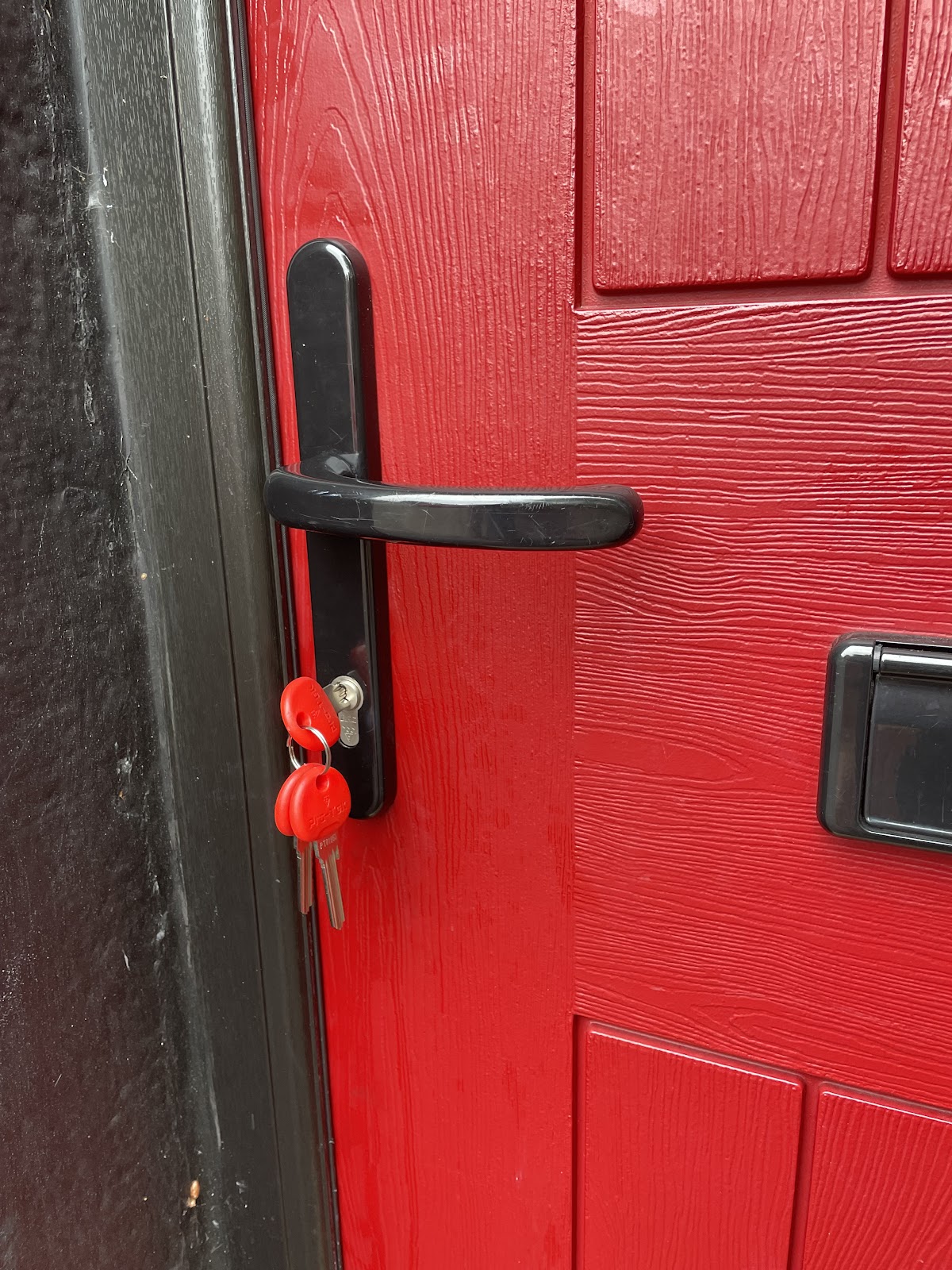 Red uPVC door with new black handle fitted